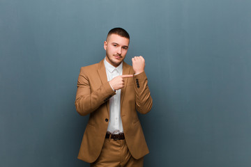 young handsome businessman looking impatient and angry, pointing at watch, asking for punctuality,...