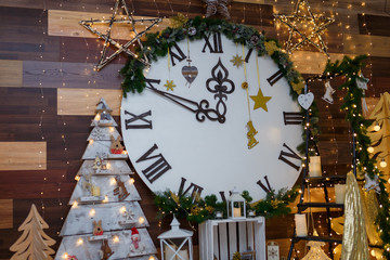 Big decorative clock on the wall with shiny stars, garland lights, wooden toys and candles. Merry Christmas or Happy New Year eve concept. Winter holidays. 