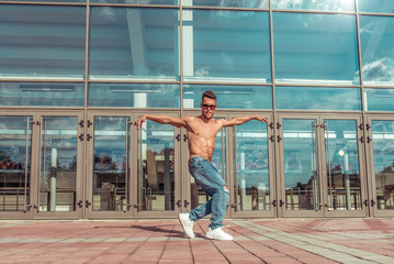 Fototapeta na wymiar Young active dancer, trained tanned torso, sport man, summer city, pose break dancer, hip-hop movement, modern dance style, youth lifestyle. Street urban fitness motivation. Free space for copy text.