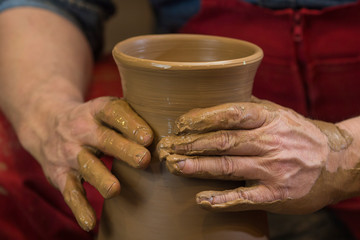 Professional male potter making ceramics on potters wheel in workshop, studio. Close up shot of...