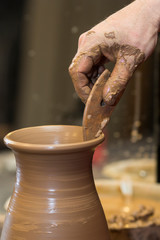 Fototapeta na wymiar Professional male potter making ceramics on potters wheel in workshop, studio. Close up shot of potters hands. Handmade, art and handicraft concept