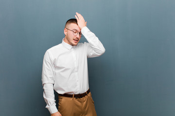 young handsome businessman raising palm to forehead thinking oops, after making a stupid mistake or...