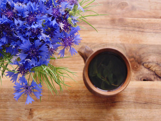 Obraz na płótnie Canvas Blue cornflowers and a cup of mint tea