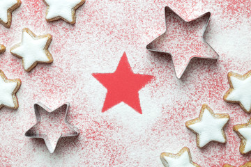 Flat lay of christmas star cookies with cutters and sugar powder in form of snow on red background minimal creative concept.