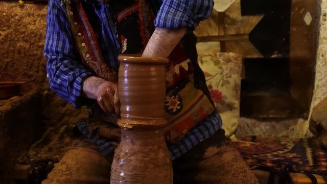 Potters wheel, hands forms clay pot on potter's wheel, Experienced master doing a pot on a pottery wheel, Hands working on pottery wheel, shaping a clay pot, Traditional and Manual Pottery Production,
