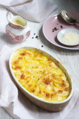French dish Gratin Dauphinois in ceramic form on a light background. Rustic style.