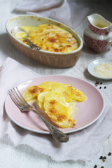 French dish Gratin Dauphinois in ceramic form on a light background. Rustic style.