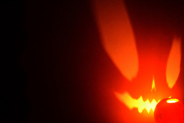 Black Halloween background with a glowing jack-o-lantern. A glint of light on the wall.