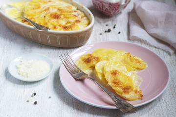 French dish Gratin Dauphinois in ceramic form on a light background. Rustic style.