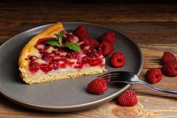 Closeup piece of homemade raspberry pie with yogurt filling on wooden table. Shallow focus.