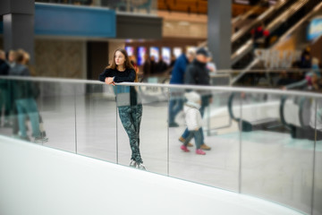 Teenager. Young pretty white caucasian teenage girl with long hair with problem skin and long hair in a shopping center near the railing.