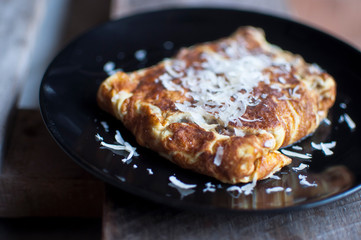 Egg omelete on black plate with grated cheese.