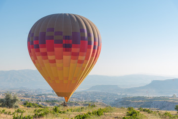 One hot air balloon flying low over the field. Copy space, Cappdocia, Turkey.