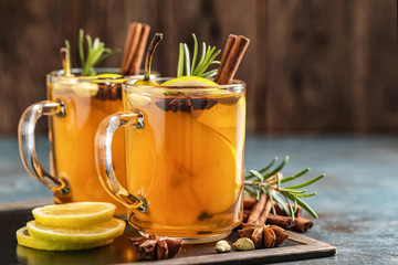 Hot drink cocktail for New Year, Christmas, winter or autumn holidays..Toddy. Mulled pear cider or spiced tea or grog with lemon, pear, cinnamon, anise, cardamom, rosemary. - obrazy, fototapety, plakaty