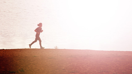 Full length portrait of woman runner with beautiful figure doing daily evening run at ocean