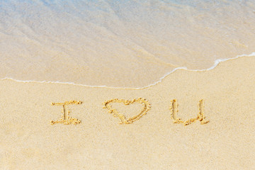 Valentine's day on a sunny beach. Text I love you. Declaration of love in the sand, washed away by the sea wave. Love concept. Relax on the sandy beach. Copy space.