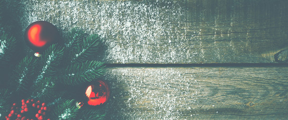 Christmas background for greeting card with Christmas tree branches, decoration and red balls, on rustic wooden table. Top view with copy space for text.