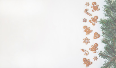 Christmas or winter composition. Border made of gingerbread cookies and spruce branches on pastel background. Christmas, winter, new year concept. Flat lay, top view, copy space.