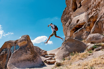 Man with backpack jumping from rock to another. Traveler concept.