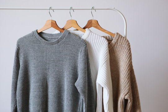 Warm Sweaters On A Wardrobe Hanger On A Light Background. Autumn, Winter Clothes.