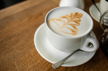 A Cup of cappuccino close-up on a wooden table in a cafe.