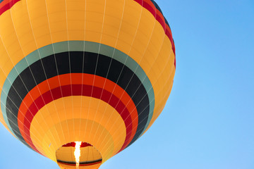 Obraz premium Close up shot of hot air balloon flying up high against blue clear sky. View from below.