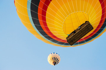 Close up shot of hot air balloon flying up high against blue clear sky. View from below.