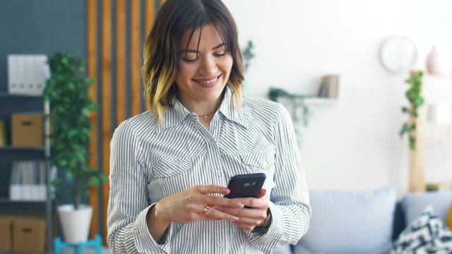 Young Businessman Woman Stay in Modern Office or Living Room with Smartphone in his Hand. Girl Using Phone for Work or Social Network.