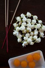 Fragrant jasmine blossom garland wrapped in circle on wooden table traditionally used as an offering to the ghosts and spirits in Thailand.