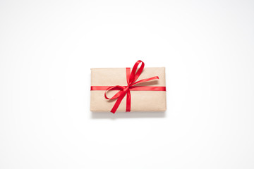 Gift isolated on a white background, Packed in brown paper and decorated with a red ribbon with a bow, there is a place for the inscription. The concept of surprises and gifts.