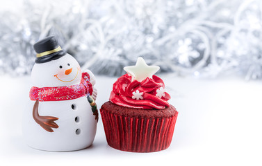 Merry Christmas and Happy New Year with red cupcake and snowman statuette