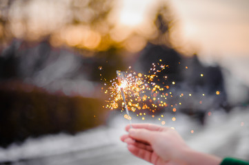 Beautiful sparklers in the hands of a girl on a city background, holiday and Christmas and New Year...