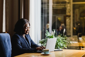 happy young african american businesswoman using computer in office - Powered by Adobe