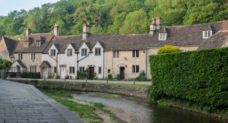 CASTLE COMBE, COTSWOLDS, UK - MAY 26, 2018: Street view of old riverside cottages in the picturesque Castle Combe Village, Cotswolds, Wiltshire, England - UK