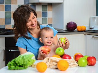 Fototapeta na wymiar Happy mother and son baby boy eat healthy vegetarian food, lots of fruit and vegetables. Healthy nutrition for children. Fruits in ecological bag.