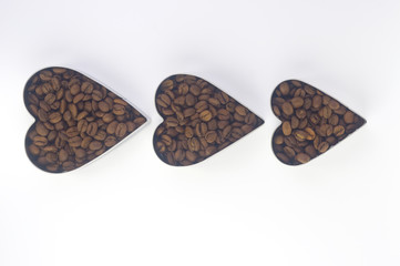  coffee beans in three tins of different sizes in the shape of a heart arranged one after another...