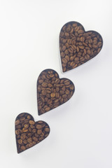 Obraz premium coffee beans in three tins of different sizes in the shape of a heart arranged diagonally one after another on a white background Flat lay