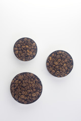 Obraz na płótnie Canvas coffee beans in three tins of different sizes and round shapes located on a white background Flat lay