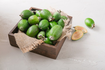 Feijoa fruit in a wooden plate on a cutting kitchen board.