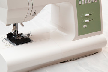 Modern sewing machine is used at home for sewing clothes.