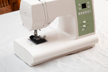 Modern sewing machine is used at home for sewing clothes.