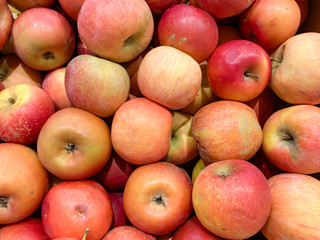Many beautiful fresh juicy red apples in a box in a supermarket as a background