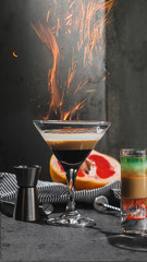 Cocktail with fire flame sparks. Dark background