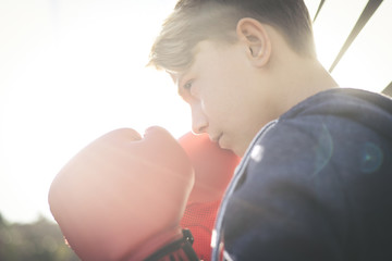 Portrait of handsome young male with boxing gloves ahead the face. Boy ready for a boxe workout defending the head with hands. Boxer ready to throw punches. Sport determination and competition concept