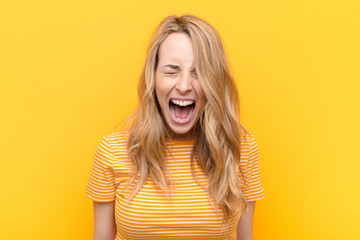 young pretty blonde woman shouting aggressively, looking very angry, frustrated, outraged or...