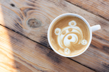 Mug of coffee on a wooden table. Cappuccino with a bear pattern. Flat lay