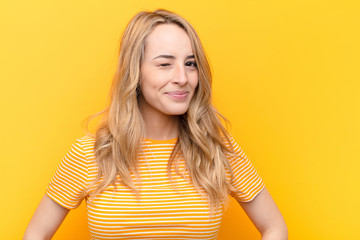 young pretty blonde woman looking happy and friendly, smiling and winking an eye at you with a...