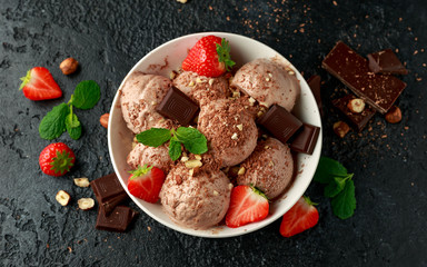Chocolate Ice Cream with dark chocolate bars, strawberry and hazelnuts in a white bowl