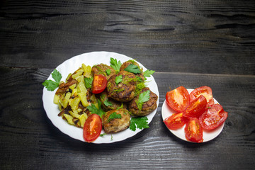 fried potatoes with vegetables and meatballs and red tomatoes sliced
