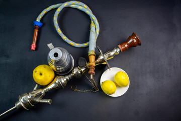 hookah is an oriental smoking device in which the smoke passing through the water is cooled, on a black background next to fresh fruit
